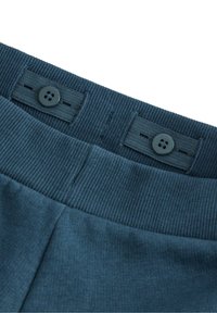 Dunkelblaue Hose mit geripptem Bund, ausgestattet mit zwei schwarzen Knöpfen und Nähdetails. Das Material wirkt weich und strukturiert.