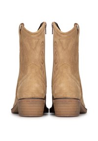 Botas de tobillo de ante color tostado con un tacón bajo en bloque, patrones de costura decorativa y lengüetas en la parte superior para facilitar su uso.