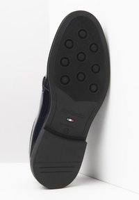 Black rubber shoe sole with circular grip patterns, embossed brand name "Nero Giardini," and Italian flag detail. Made in Italy.