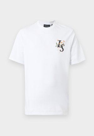 Hvit t-skjorte med korte ermer og rund hals, med liten "LS"-logo og blomstermotiv på venstre bryst, vist på en ensfarget lys bakgrunn.