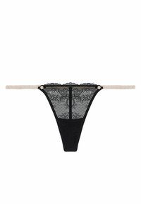 Černé krajkové tanga s květinovým vzorem, s průhledným zadním dílem a tenkými krémovými ramínky, zdobené malým knoflíkovým akcentem.