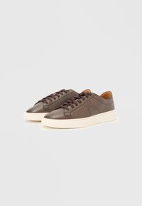 Brown leather sneakers with a smooth texture, round toe, and contrasting cream rubber sole. Features brown laces and side detailing.