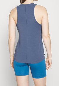 Granatowy top na ramiączkach, bez rękawów, z zaokrąglonym dołem i pionowym szwem na środku; w komplecie z niebieskimi szortami.