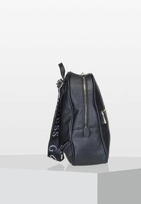 Sac en cuir noir texturé, avec fermeture éclair, quincaillerie en acier inoxydable et une bandoulière à motif portant le nom de la marque. Forme rectangulaire.