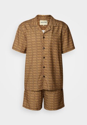 Conjunto de camisa de manga curta e calções castanhos com um padrão geométrico repetido em castanho escuro. Fecho por botão e tecido macio e suave.