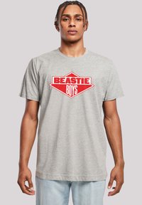 Gray cotton t-shirt featuring a red graphic logo with "BEASTIE" above "BOYS" in a diamond shape. Short sleeves and crew neckline.