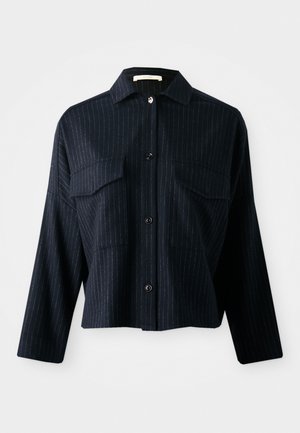 Camicia di cotone blu navy con righe bianche verticali, maniche lunghe, chiusura con bottoni, due tasche sul petto e colletto. Tessuto liscio.
