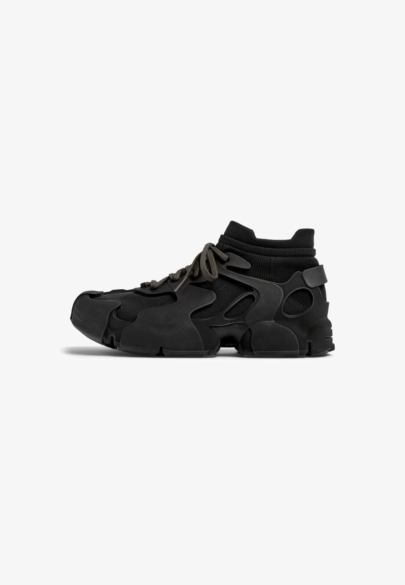 Black sneaker featuring a molded design with cut-out sections, textured fabric collar, and thick laces, providing a modern, athletic appearance.