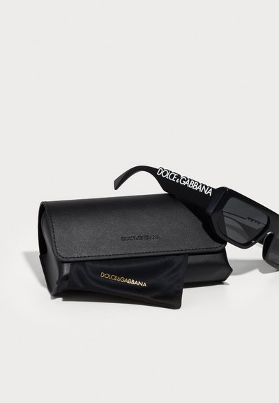 Melni saulesbrilles ar stūra rāmjiem, ar baltu "DOLCE&GABBANA" zīmolu uz kājiņām. Komplektā iekļauts melns mākslīgās ādas maciņš un drāna.