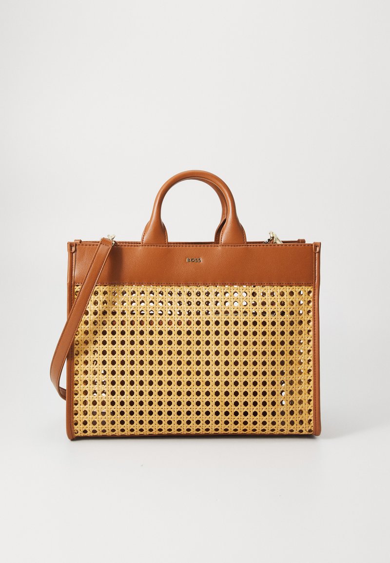 Brown leather handbag with a woven rattan front. Features dual top handles, a removable shoulder strap, and a zip closure.