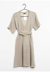 Beige stickad klänning med djup V-ringning, korta ärmar och figursydd midja. Har ett matchande bälte och en texturerad tyg. Tagg fäst.