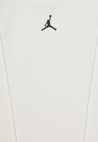 Vit ribbad linne med en liten svart broderad Jumpman-logotyp i mitten. Lättviktsmaterial med en mjuk textur.