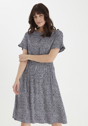 Blumengemustertes Kleid in Marineblau und Weiß, mit kurzen Ärmeln, gerafftem Taillenbereich und einem schwingenden Rock, der unterhalb der Knie endet.