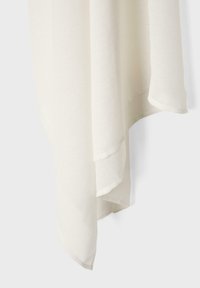 Tissu crème clair avec une surface douce et texturée, suspendu en plis légers sur un fond uni.