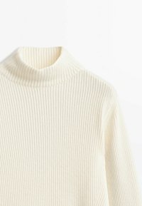 Pull en tricot côtelé écru avec un col montant haut et des manches longues, présenté sur fond blanc.