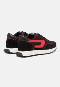 Baskets en daim noir et tissu avec des accents rouges, dotées d'une semelle blanche et d'une semelle extérieure en caoutchouc noir. Le design présente une silhouette rétro élégante.