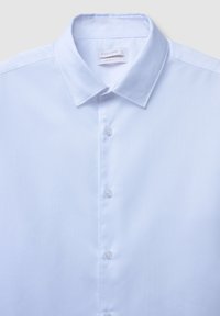 Camicia bianca slim fit con colletto a punta e bottoni visibili lungo il davanti, etichetta all'interno del colletto con la scritta "Calliope L."