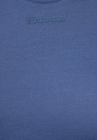 Blauw gestructureerde stof met subtiel honingraatpatroon en verhoogd "hummel"-logo en gestileerd bijenpictogram geperst nabij het bovenste midden.