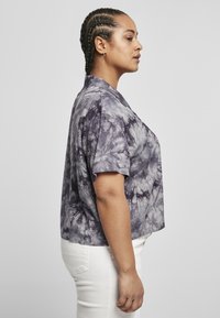 Koszulka krótki rękaw, skrócona, w wzór tie-dye, w odcieniach fioletu i szarości, wykonana z miękkiego materiału; posiada kołnierzyk i luźny krój.