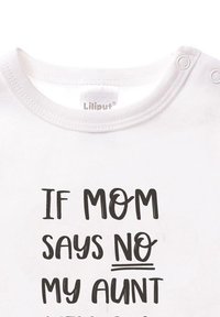 Weißer Baby-Body mit schwarzem Textdruck: "WENN MOM NEIN SAGT, SAGT MEINE TANTE JA." Glatte Stoffqualität mit Druckknöpfen an der Schulter.