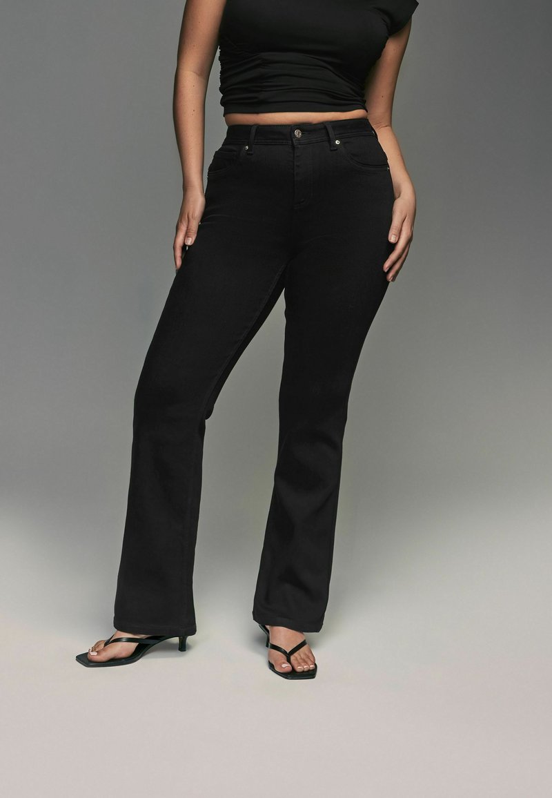 Svarta jeans med utsvängda ben och midja som sitter i midjehöjd, framfickor och silverdetaljer. Matchat med en figurnära svart crop top och svarta sandaler.