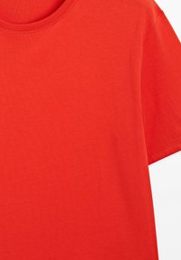 T-shirt rouge vif à manches courtes avec un col rond et des coutures visibles sur le col et les bords des manches.