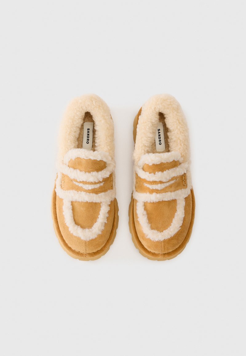 Bruine suède schoenen met fluffy crème-kleurige voering en accenten. Rondneus ontwerp met dubbele bandjes en gespen en textuur rubberen zolen.
