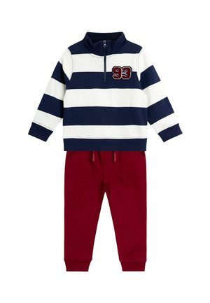 Zweiteiliges Outfit mit einem navy- und weißen gestreiften Langarmpullover, der einen halben Reißverschluss und die Nummer 93 aufweist, kombiniert mit bordeauxfarbenen Jogginghosen.