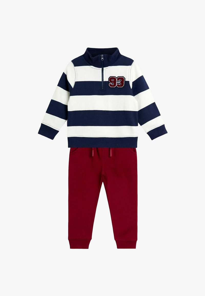 Zweiteiliges Outfit mit einem navy- und weißen gestreiften Langarmpullover, der einen halben Reißverschluss und die Nummer 93 aufweist, kombiniert mit bordeauxfarbenen Jogginghosen.