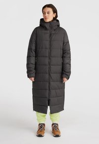 Lång svart pufferjacka med huva, med horisontella kviltade sektioner, sidofickor med dragkedja och en heldragkedja fram.
