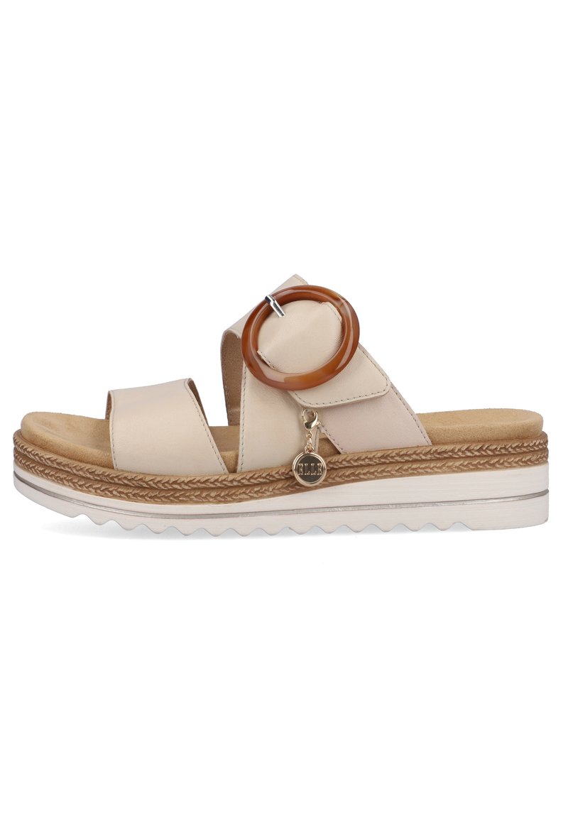 Helle beigefarbene Sandalen mit einem breiten Riemendesign, das ein braunes ovales Akzent und einen kleinen dekorativen Anhänger aufweist, auf einer strukturierten Sohle.