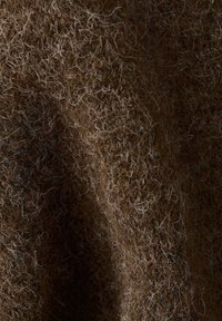 Tessuto marrone con una texture morbida e calda, con fibre chiare mescolate, creando un aspetto ricco e stratificato.