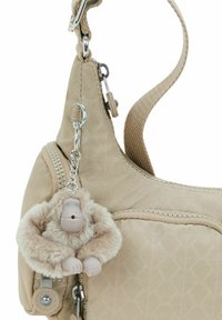 Beige Handtasche aus strukturiertem Stoff mit einem Reißverschlussfach. Akzentuiert durch einen flauschigen Affen-Schlüsselanhänger und silberne Beschläge.