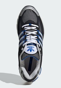 Scarpa da corsa in rete nera con dettagli argentati, strisce blu e lacci bianchi. Presenta un collare imbottito e una suola testurizzata.