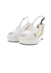 Bílé plátěné klínové sandály s otevřenou špičkou, slingback páskem a texturovaným espadrilovým klínem. Obsahují stříbrný přívěsek a černé akcenty.
