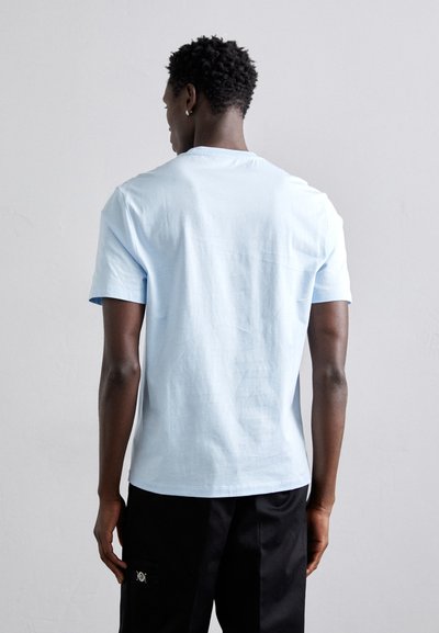 Ljusblå bomulls t-shirt med korta ärmar, rund hals och en avslappnad passform. Slät textur, minimal design, utan synliga tryck.