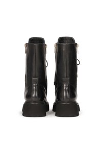 Stivaletti neri in pelle con finitura liscia, cerniere laterali, suole spesse e cuciture decorative lungo i bordi.