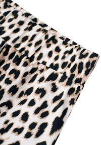 Tkanina s uzorkom leoparda u bež i crnoj boji, s glatkom teksturom, mekanim završetkom, i skupljenim pojasom za rastezanje i udobnost.