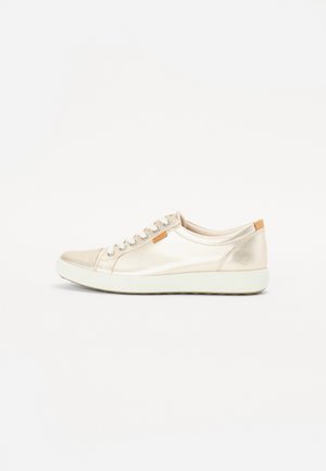 Glat, metalen beige sneaker met vierkante neus, gladde textuur, tonale stiksels, zes oogjes en een tan accent op de hiel. Witte rubberen buitenzool.