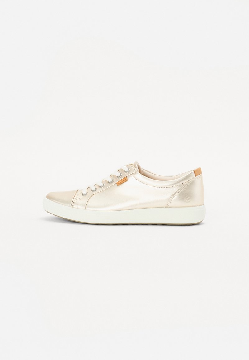 Glat, metalen beige sneaker met vierkante neus, gladde textuur, tonale stiksels, zes oogjes en een tan accent op de hiel. Witte rubberen buitenzool.