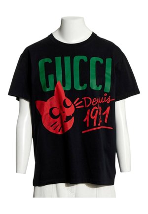 T-shirt noir à manches courtes avec un grand texte vert "GUCCI", visage de chat dessin animé rouge et écriture rouge "Depuis 1911" sur le devant.