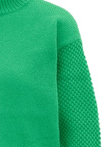 Grüner Strickpullover mit einem strukturierten Muster an einem Ärmel und einer glatten Oberfläche am Rumpf, mit einem hohen, gerippten Halsauschnitt.