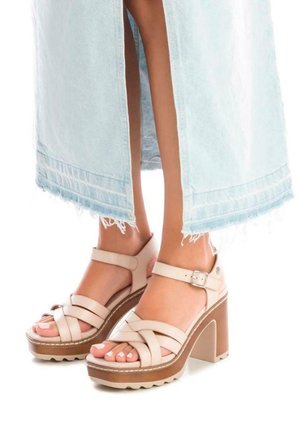 Sandali platform beige con fasce incrociate, cinturino alla caviglia regolabile e tacco alto. Suola testurizzata per una buona aderenza. Abbinati a una gonna in denim chiaro.