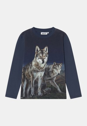 Marineblå skjorte med lange ærmer med to realistiske ulve, der står på klipper mod en mørk, bjergrig baggrund.