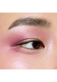 Gros plan sur un œil avec un fard à paupières rose doux se fondant dans des tons plus clairs ; texture de peau lisse, sourcil bien défini et iris brun foncé.