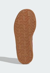 Smeđa gumena potplatica cipele s valovitim i pravokutnim uzorkom gaznoga sloja, utisnuti Adidas logo blizu pete.