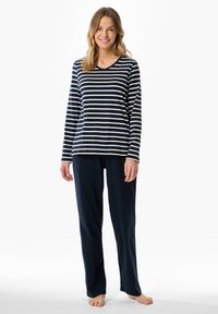 Långärmad navy- och vitrandig pyjamatröja med V-ringning, i kombination med enfärgade navy-byxor. Mjuk tyg, avslappnad passform och inga synliga mönster.