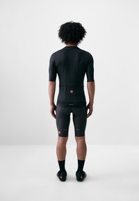 Completo ciclistico da uomo nero con maniche corte e design aderente. Realizzato in un tessuto liscio e elasticizzato con dettaglio del logo sulla schiena.