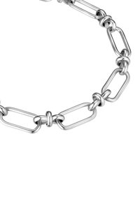 Pulsera de cadena de metal plateado con eslabones ovalados y redondos, con una superficie lisa y pulida, y un detalle de nudo central.