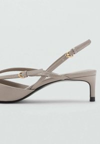 Beige sandaalit, joissa on alhainen korko ja ohuet hihnat, valmistettu sileästä materiaalista. Varustettu kultaisilla yksityiskohdilla ja tyylikkäällä, minimalistisella muotoilulla.